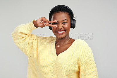 Buy stock photo Shot of a young woman wearing headphones while posing against a grey background