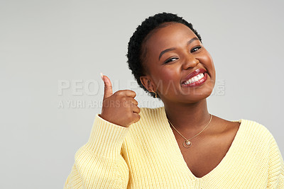 Buy stock photo Closeup shot of a beautiful young woman showing thumbs up while standing against a grey background
