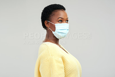 Buy stock photo Shot of a young woman wearing a surgical mask while standing against a grey background