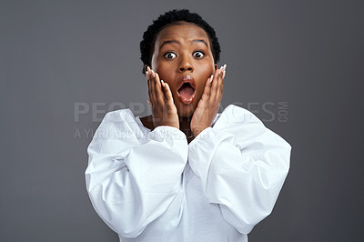 Buy stock photo Shot of a woman looking shocked while standing against a grey background