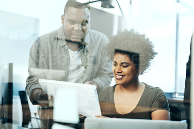 Buy stock photo Shot of two young businesspeople looking at paperwork together in the office