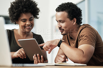Buy stock photo Shot of two young businesspeople sitting together and using a digital tablet in the office