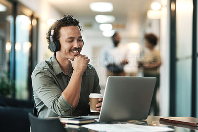 Buy stock photo Shot of a young businessman sitting in the office and wearing headphones while using his laptop for a virtual meeting