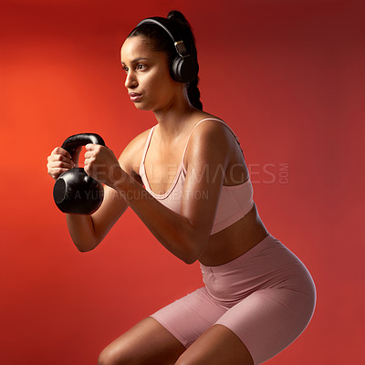 Buy stock photo Studio shot of a sporty young woman doing kettlebell squats against a red background