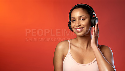 Buy stock photo Studio portrait of a sporty young woman wearing headphones against a red background