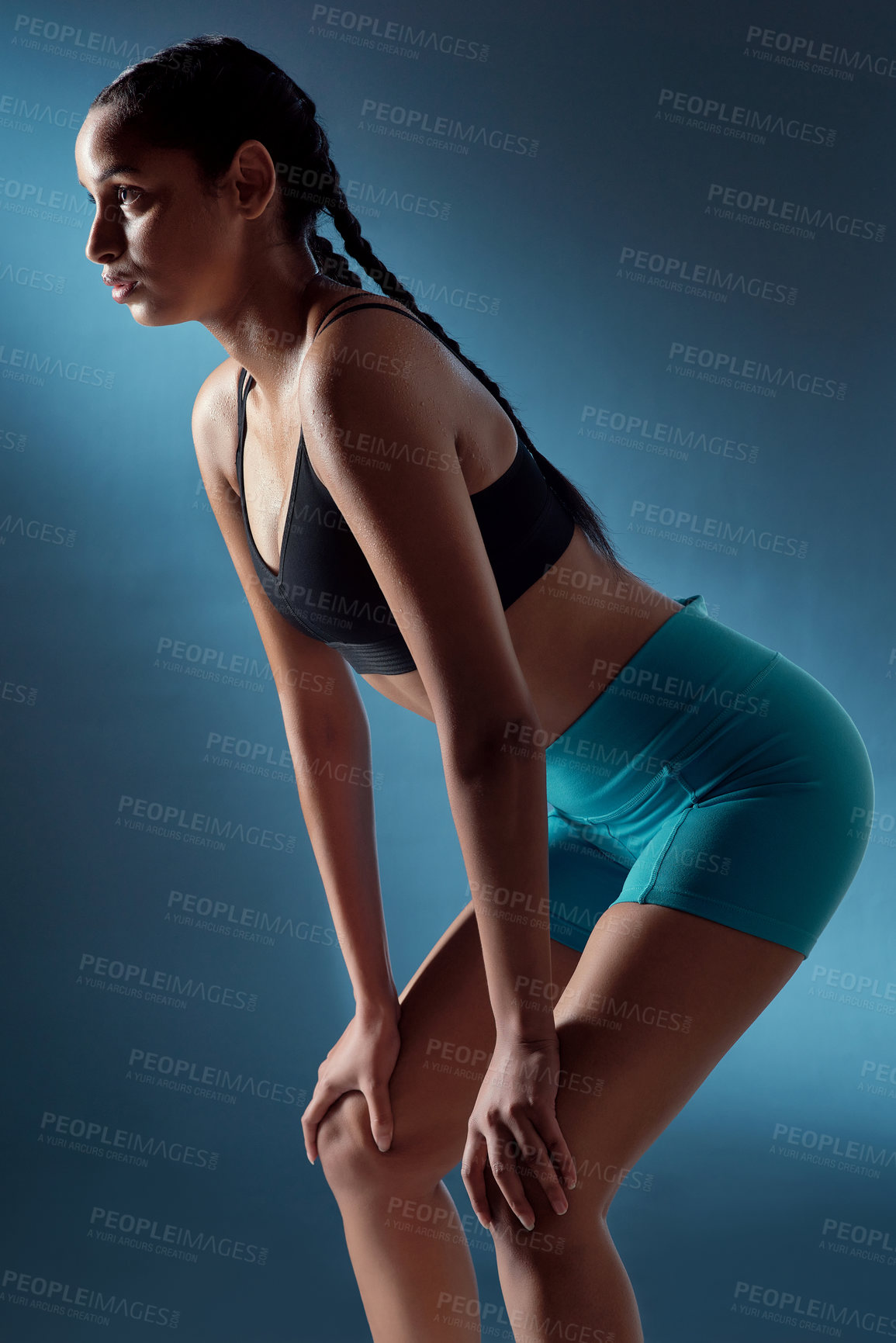 Buy stock photo Studio shot of a sporty young woman catching her breath against a blue background