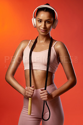 Buy stock photo Studio portrait of a sporty young woman posing with a skipping rope around her neck against a red background