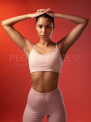 Buy stock photo Studio portrait of a sporty young woman standing with her hands on her head against a red background
