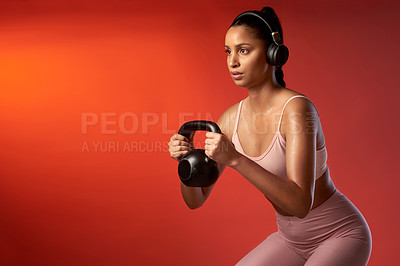 Buy stock photo Studio shot of a sporty young woman doing kettlebell squats against a red background