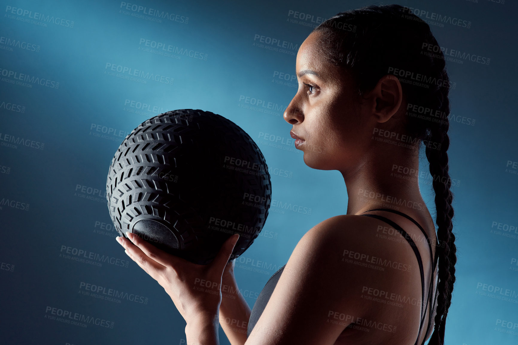 Buy stock photo Studio shot of a sporty young woman holding an exercise ball against a blue background