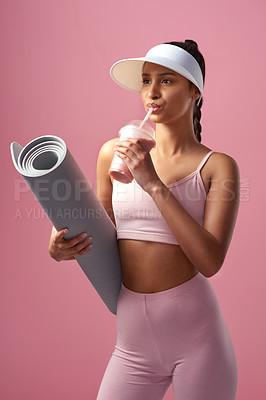Buy stock photo Cropped shot of an attractive and sporty young woman posing with an exercise mat and a smoothie in studio against a pink background