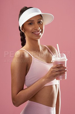 Buy stock photo Cropped portrait of an attractive and sporty young woman posing with a smoothie in studio against a pink background