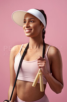 Buy stock photo Cropped shot of an attractive and sporty young woman posing with a skipping rope in studio against a pink background