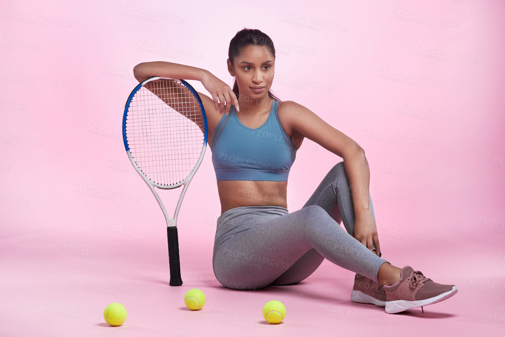 Buy stock photo Full length portrait of an attractive and sporty young woman posing with a tennis racket and tennis balls in studio against a pink background