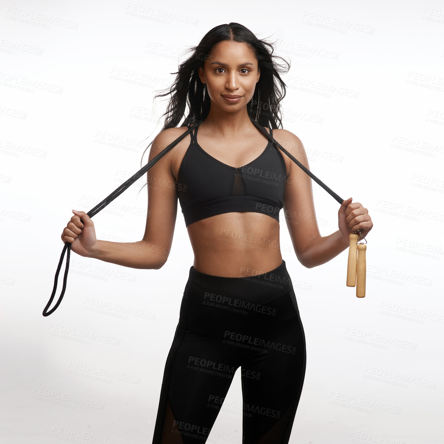 Buy stock photo Studio portrait of a sporty young woman posing with a skipping rope around her neck against a white background