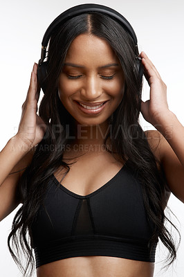 Buy stock photo Studio shot of a sporty young woman listening to music against a white background