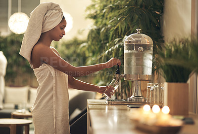 Buy stock photo Shot of a woman filling her glass at a water dispenser in a day spa