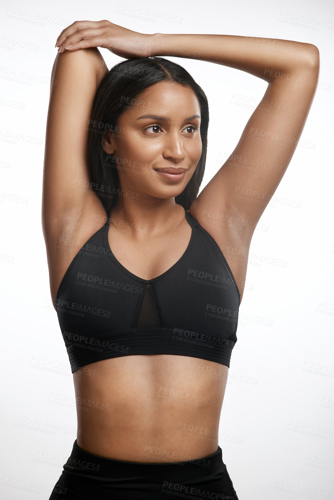 Buy stock photo Studio shot of a sporty young woman stretching her arms against a white background