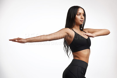 Buy stock photo Studio shot of a sporty young woman stretching her arms against a white background