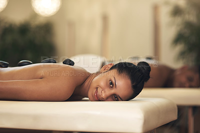 Buy stock photo Shot of a young woman getting a hot stone massage at a spa