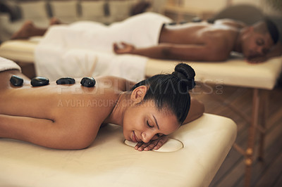 Buy stock photo Shot of a young woman getting a hot stone massage at a spa