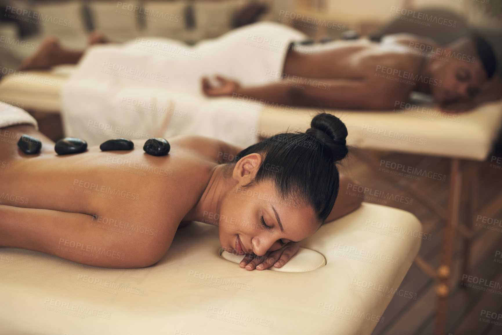 Buy stock photo Shot of a young woman getting a hot stone massage at a spa