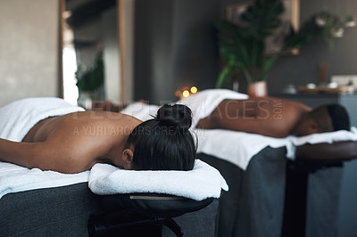 Buy stock photo Shot of a young couple lying on massage beds at a spa