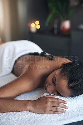 Buy stock photo Shot of a young woman getting a hot stone massage at a spa