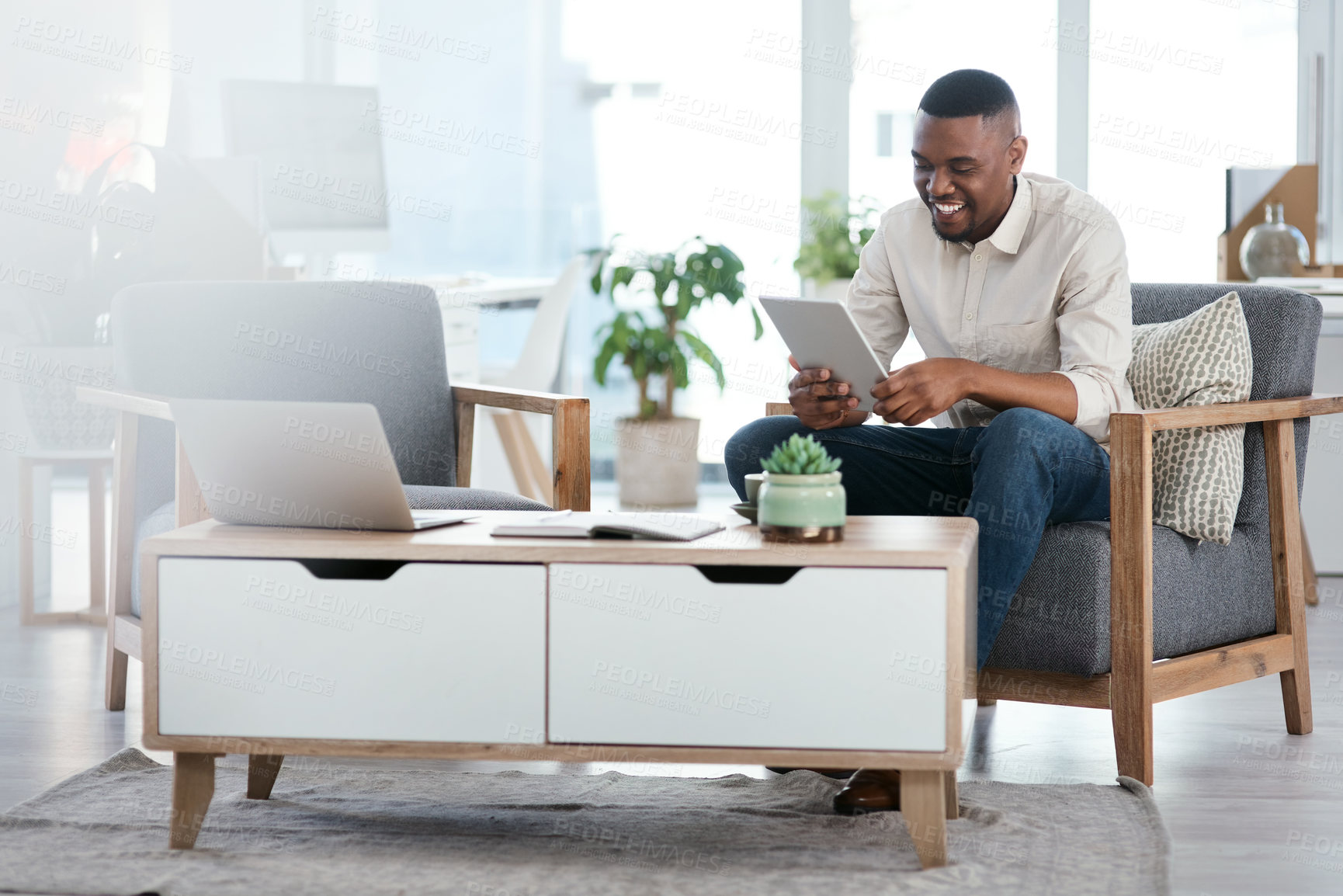 Buy stock photo Shot of a young businessman using a digital tablet in an office