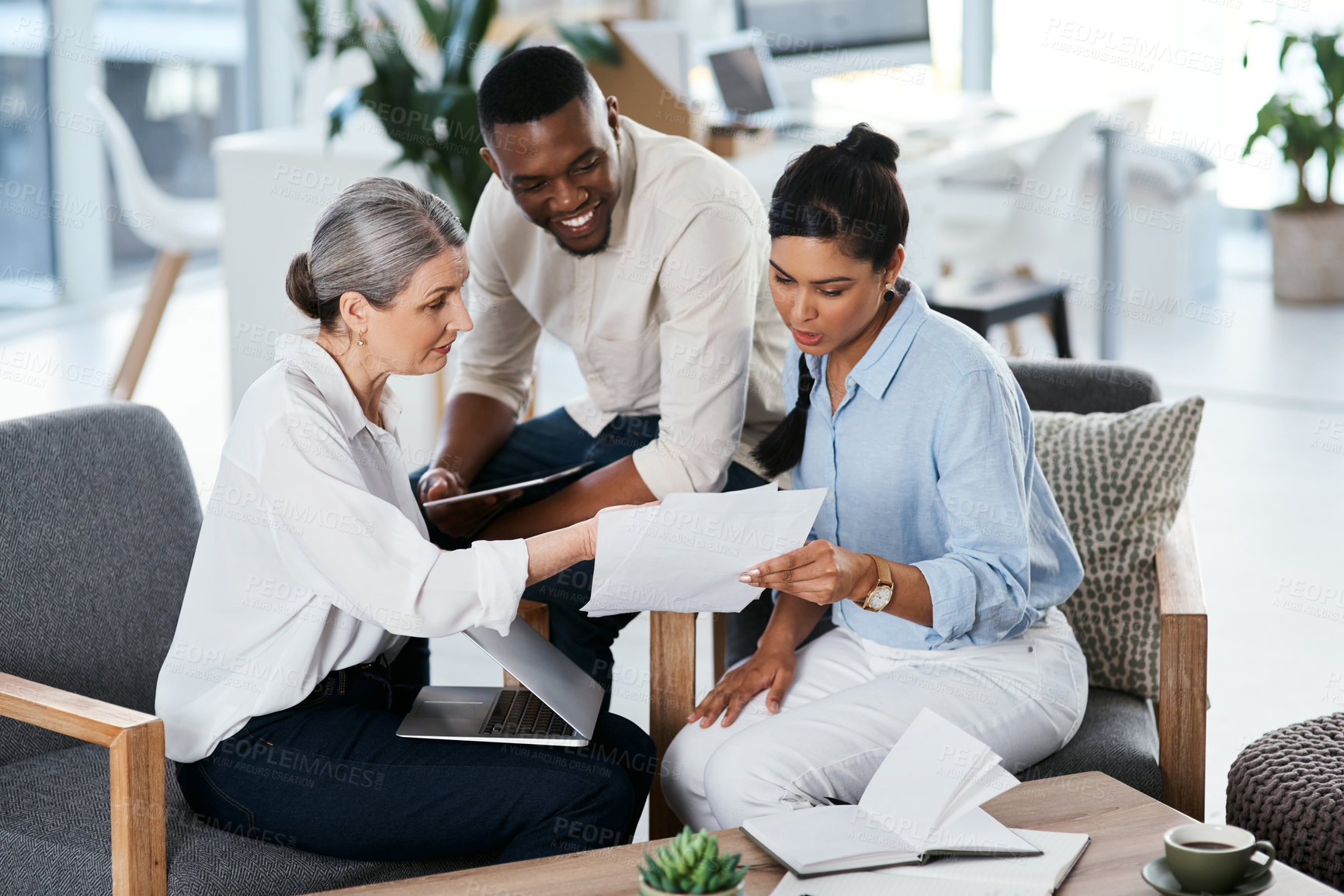 Buy stock photo Shot of a group of businesspeople going through paperwork together in an office