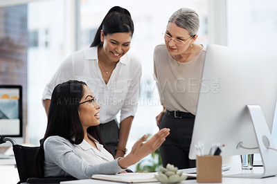 Buy stock photo Cropped shot of three diverse businesswoman talking while gathered around a desk in their office