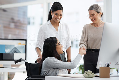 Buy stock photo Cropped shot of two businesswomen shaking hands in their office while a third colleague watches on