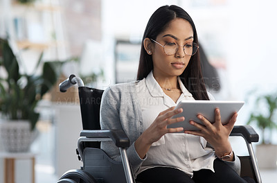 Buy stock photo Cropped shot of an attractive young businesswoman in a wheelchair using her tablet in the office