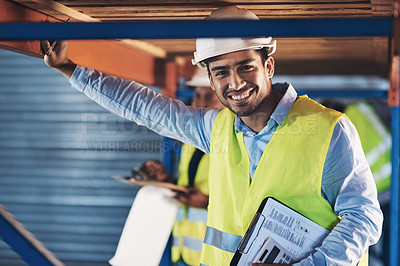 Buy stock photo Shot of a handsome young contractor standing in the warehouse and holding a clipboard