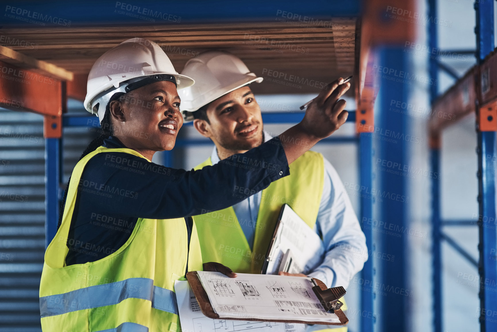 Buy stock photo Shot of two young contractors standing together and examining the scaffolding in the warehouse