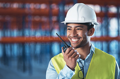 Buy stock photo Shot of a handsome young contractor standing alone in the warehouse and using a walkie talkie
