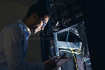 Buy stock photo Shot of a handsome young technician standing alone and looking at the mainframe