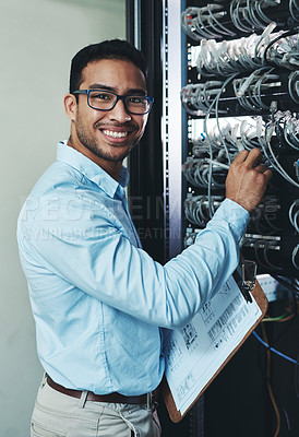 Buy stock photo Shot of a handsome young technician standing alone and adjusting the mainframe