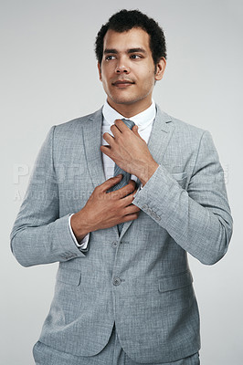 Buy stock photo Studio shot of a businessman adjusting his tie while standing against a grey background