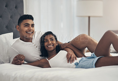 Buy stock photo Shot of a young couple laying on a bed at home