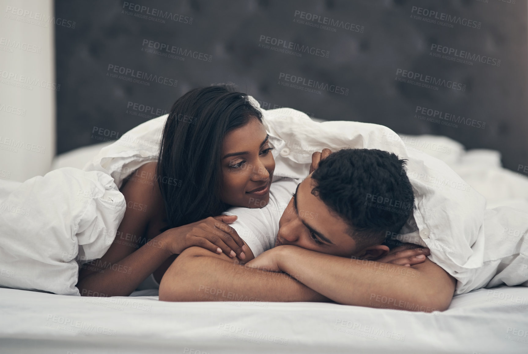 Buy stock photo Shot of a young couple laying in bed at home