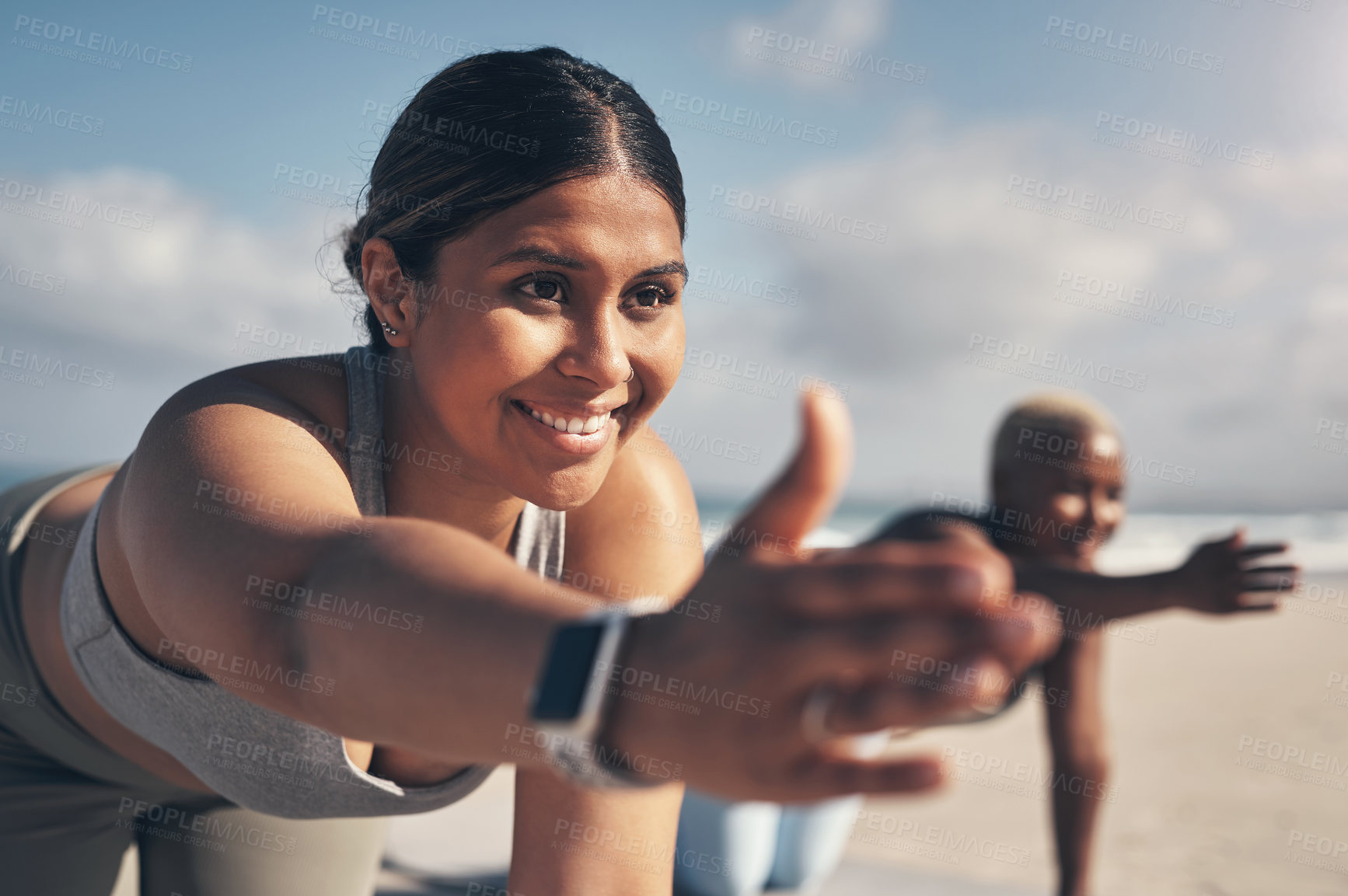 Buy stock photo Shot of a young woman wearing a smartwatch while practicing yoga at the beach