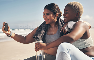 Buy stock photo Shot of two sporty young women taking a selfie while exercising at the beach