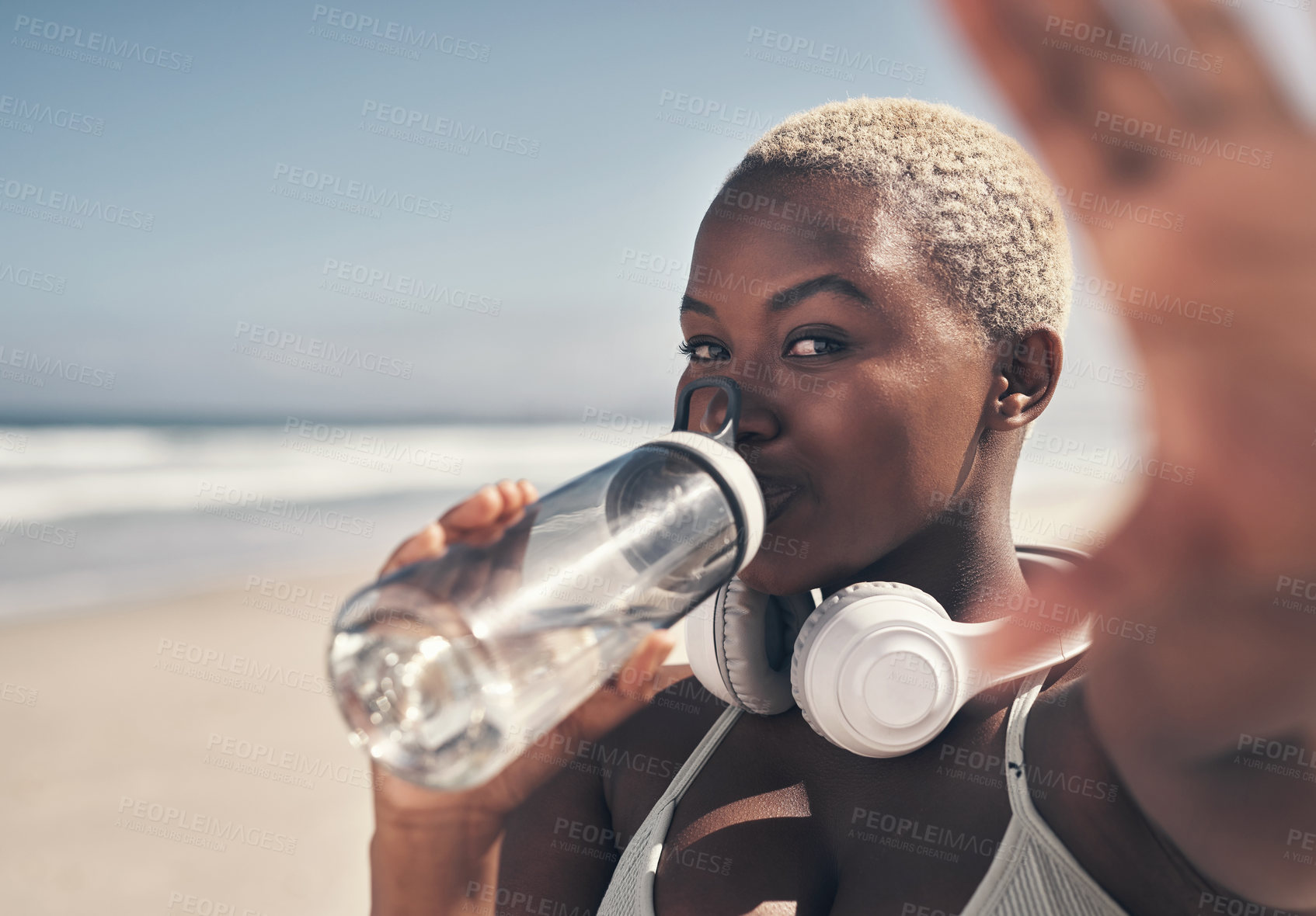 Buy stock photo Shot of a sporty young woman drinking water while out for a workout