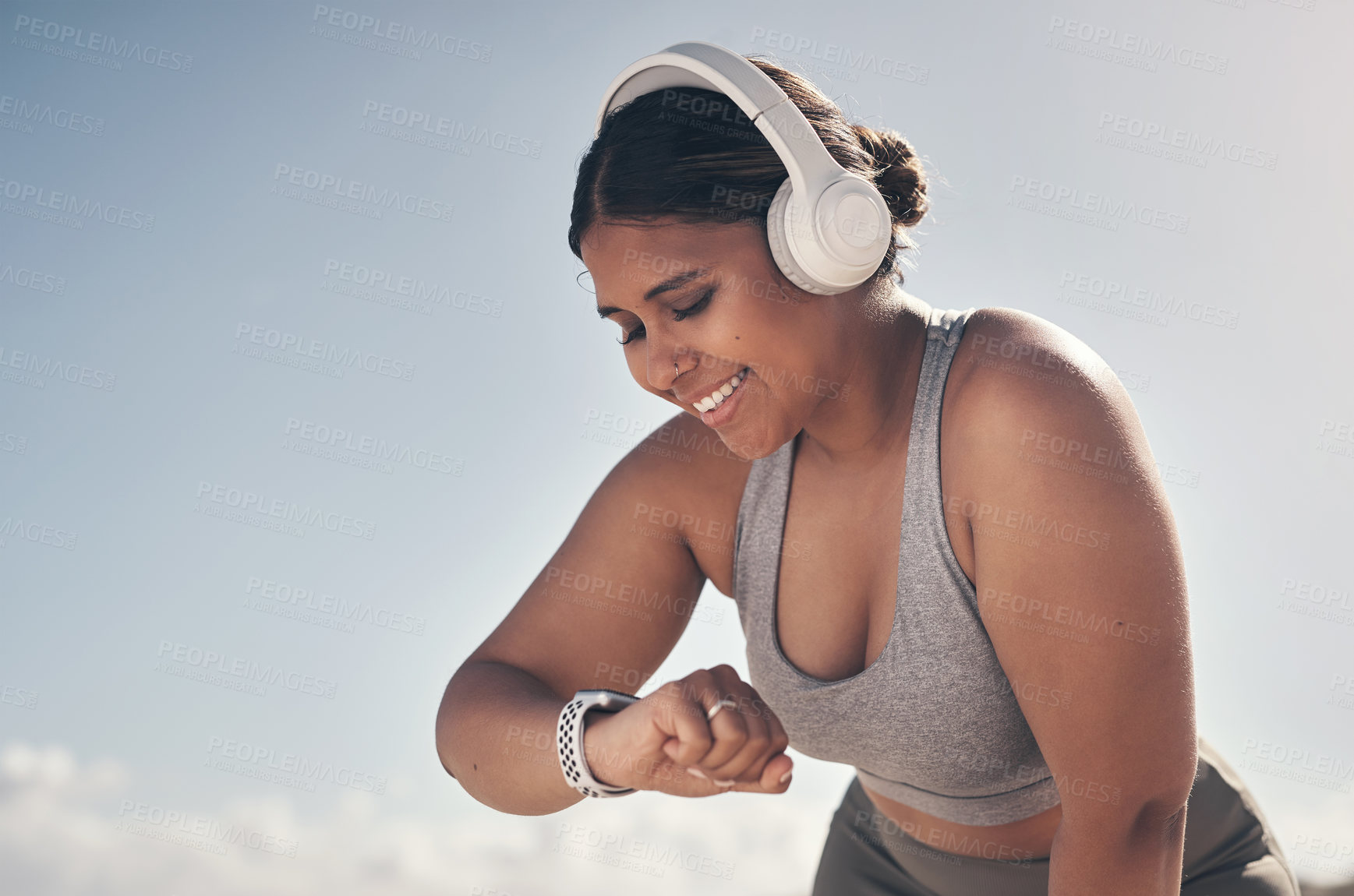 Buy stock photo Shot of a young woman wearing a smartwatch and headphones while out for a run