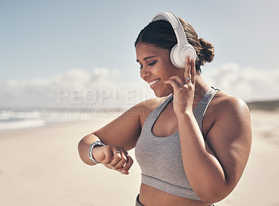 Buy stock photo Shot of a young woman wearing a smartwatch and headphones while out for a run