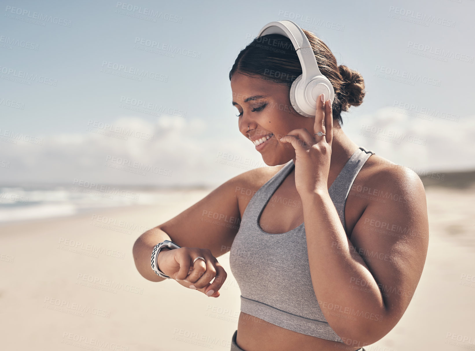 Buy stock photo Shot of a young woman wearing a smartwatch and headphones while out for a run