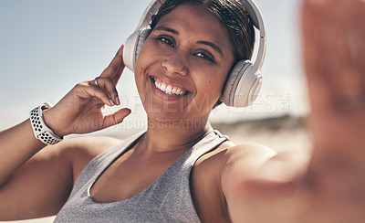 Buy stock photo Shot of a young woman wearing headphones while out for a workout