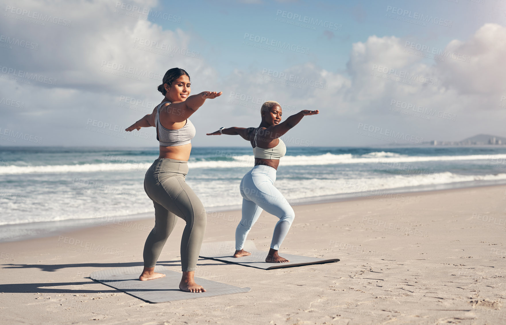 Buy stock photo Shot of two young women practicing yoga on the beach