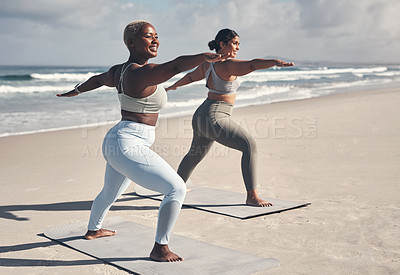 Buy stock photo Shot of two young women practicing yoga on the beach